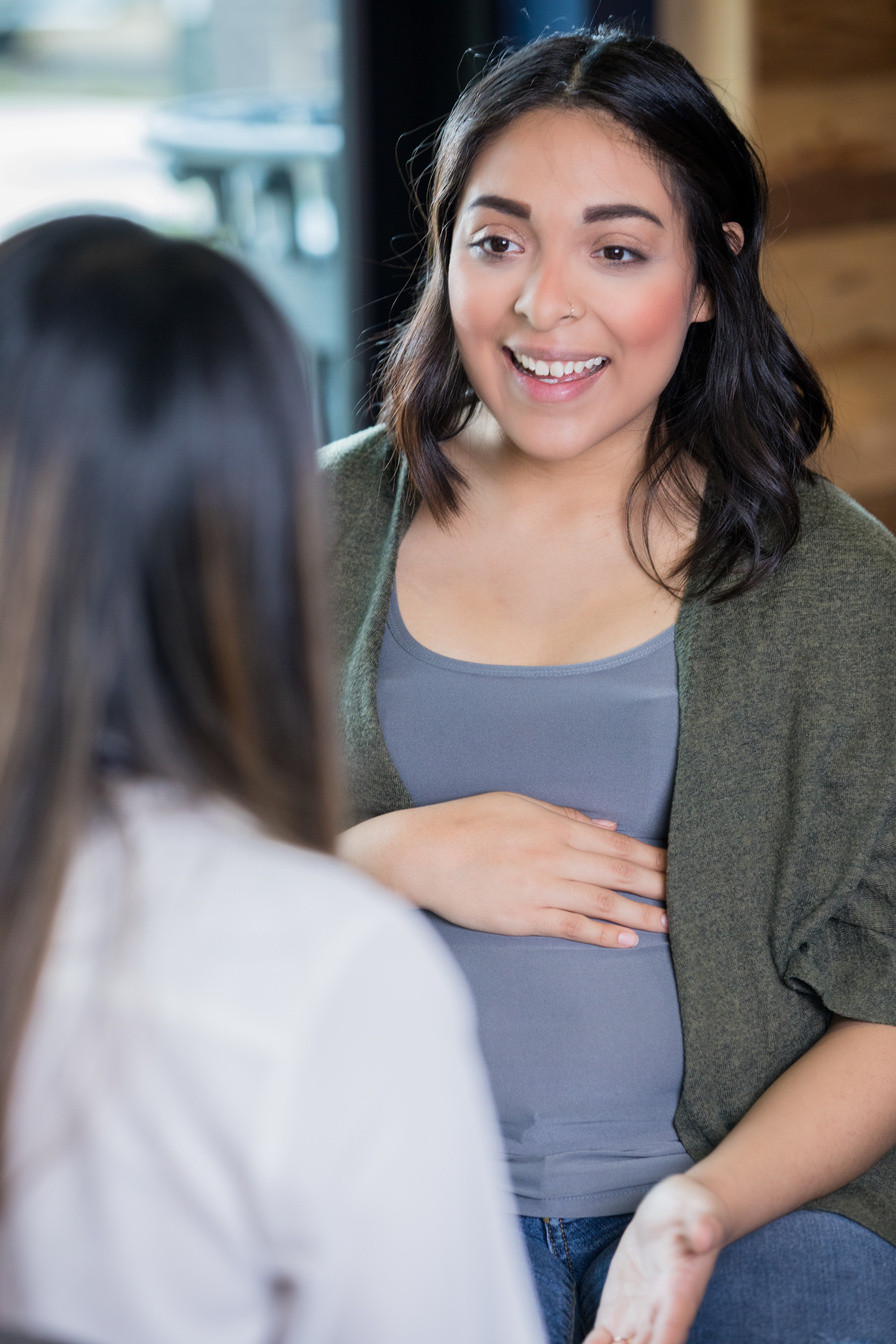 Pregnant Hispanic mother talking with midwife or doula during prenatal appointment
